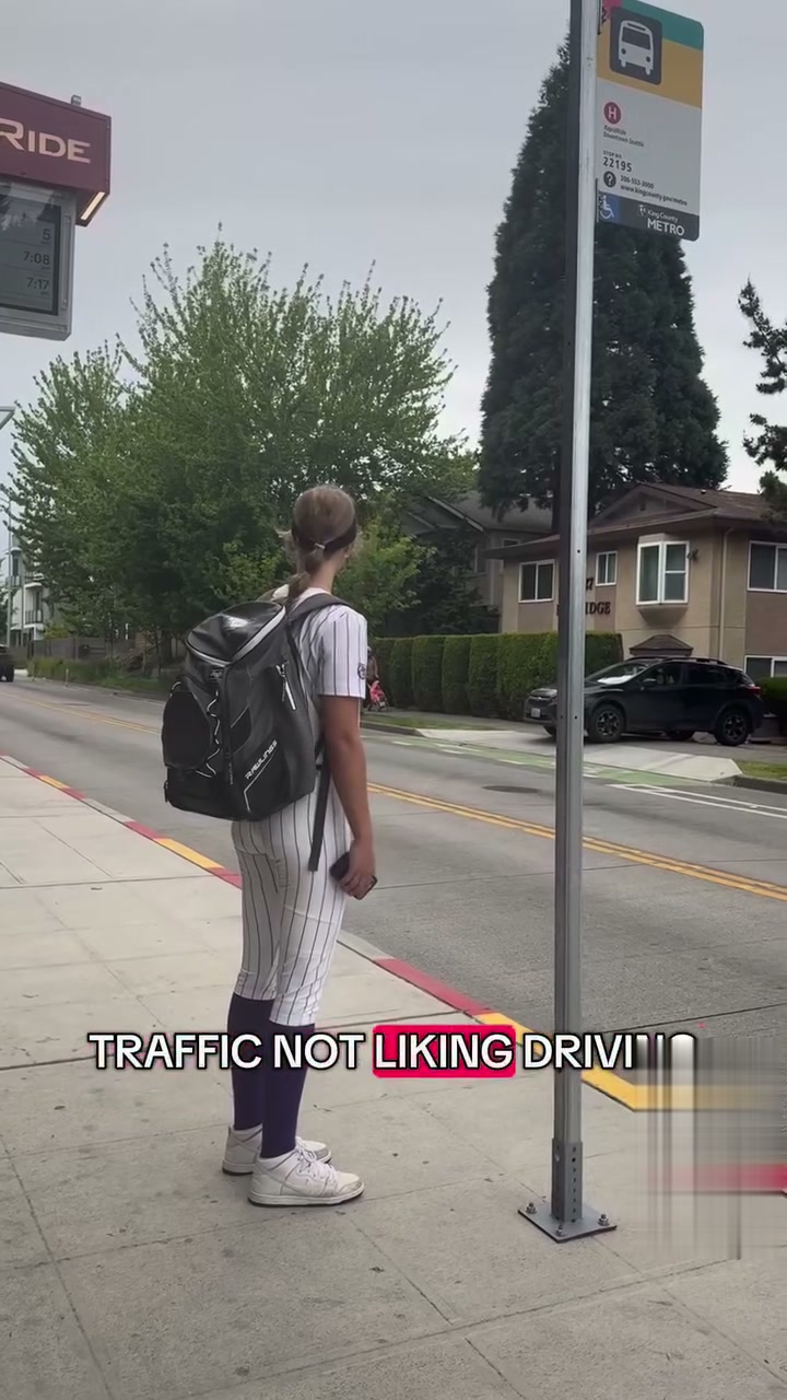 A young athlete in uniform waiting at a King County Metro bus stop after practice